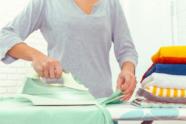 Primer plano de mujer planchando ropa en tabla de planchar