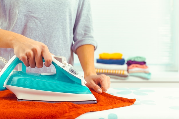 Primer plano de mujer planchando ropa en tabla de planchar