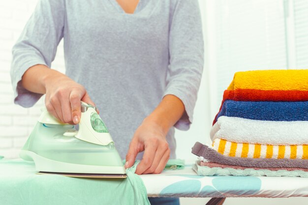 Primer plano de mujer planchando ropa en tabla de planchar