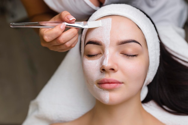 Primer plano de una mujer que recibe tratamiento facial con máscara de arcilla Cosmetología y spa