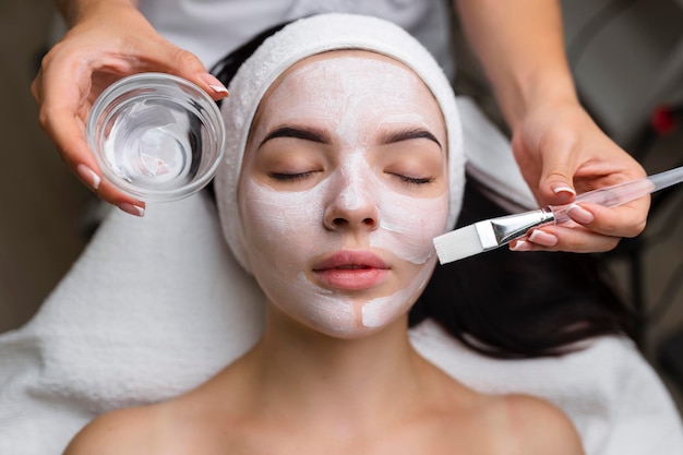 Primer plano de una mujer que recibe tratamiento facial con máscara de arcilla Cosmetología y spa