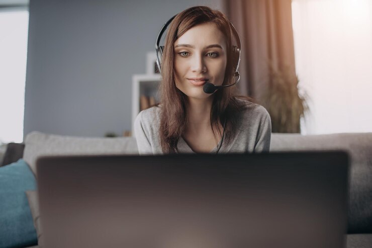 Primer plano de una mujer que usa auriculares mientras trabaja en una computadora portátil