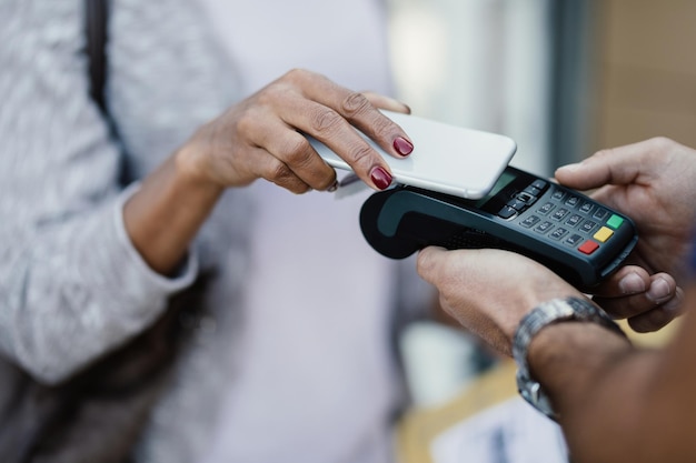 Primer plano de una mujer que usa un teléfono inteligente mientras realiza un pago sin contacto a un repartidor