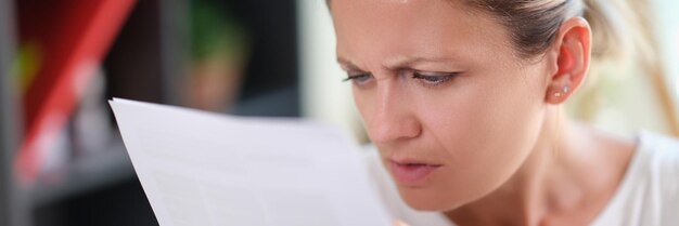 Primer plano de mujer con rostro serio leyendo administrador de documentos o empresaria cheques financieros