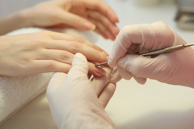 Primer plano de una mujer en un salón de uñas recibiendo una manicura