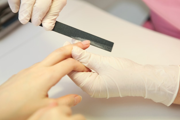 Primer plano de una mujer en un salón de uñas recibiendo una manicura