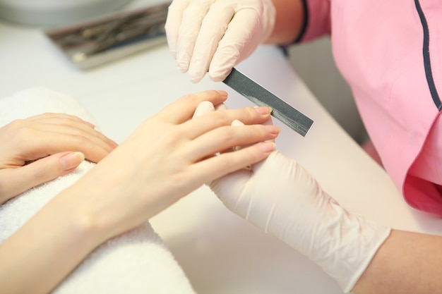 Primer plano de una mujer en un salón de uñas recibiendo una manicura