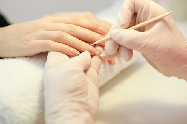 Primer plano de una mujer en un salón de uñas recibiendo una manicura