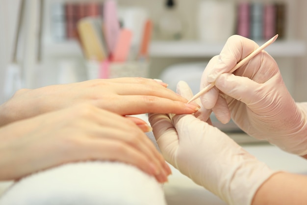 Primer plano de una mujer en un salón de uñas recibiendo una manicura