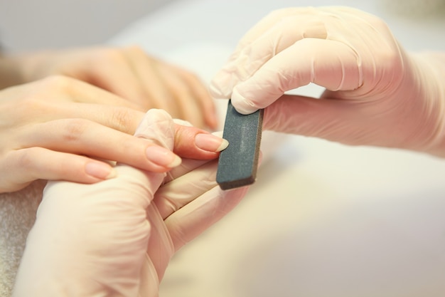 Primer plano de una mujer en un salón de uñas recibiendo una manicura