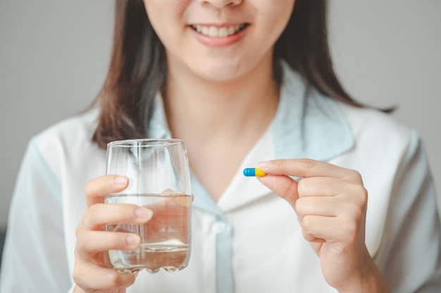 Primer plano de mujer sonriente sosteniendo píldora cápsula