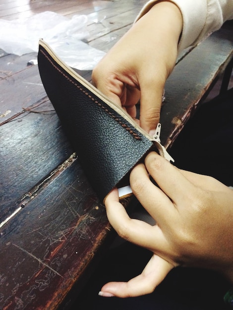 Primer plano de una mujer sosteniendo una bolsa de cuero en la mesa