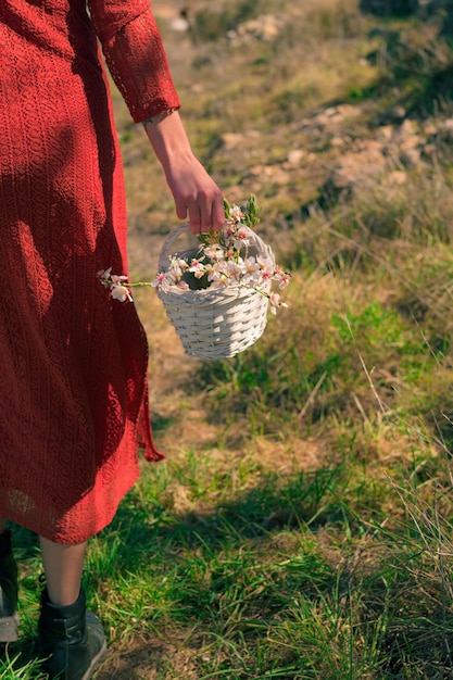 Primer plano de una mujer sosteniendo una cesta blanca con flores de almendro