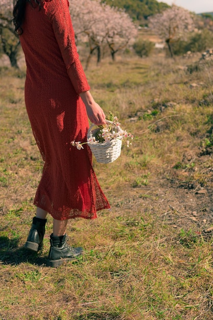 Primer plano de una mujer sosteniendo una cesta blanca con flores de almendro