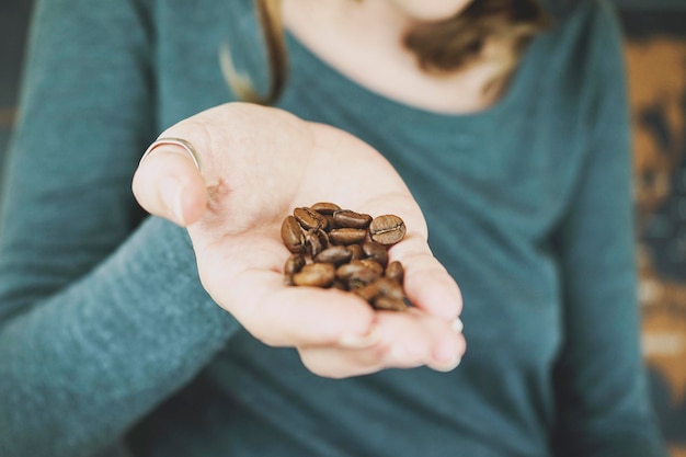 Foto primer plano de una mujer sosteniendo granos de café