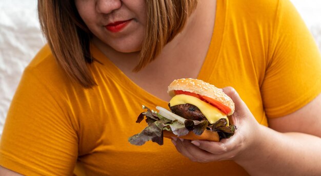 Primer plano de una mujer sosteniendo una hamburguesa