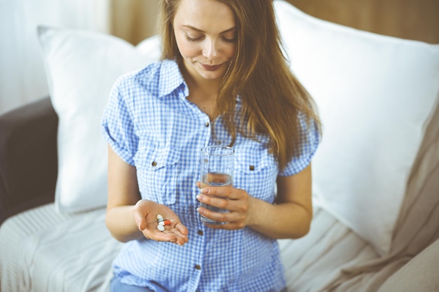 Primer plano mujer sosteniendo pastillas tiempo para tomar medicamentos, curar el dolor de cabeza, la presión arterial alta o el nivel de colesterol remediar los analgésicos. Concepto de medicina.