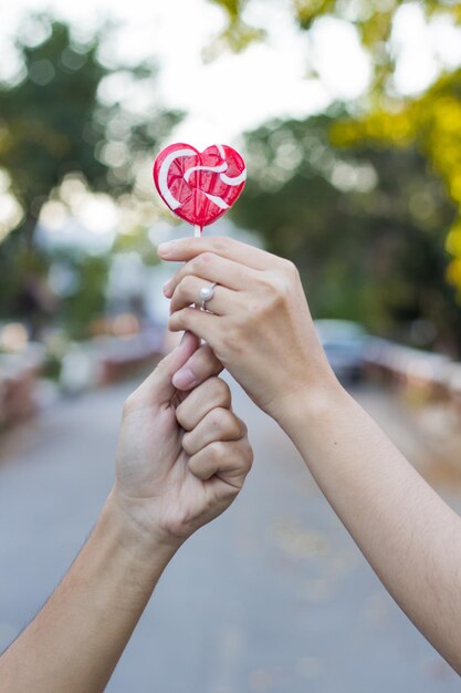 Foto primer plano de una mujer sosteniendo una piruleta en forma de corazón