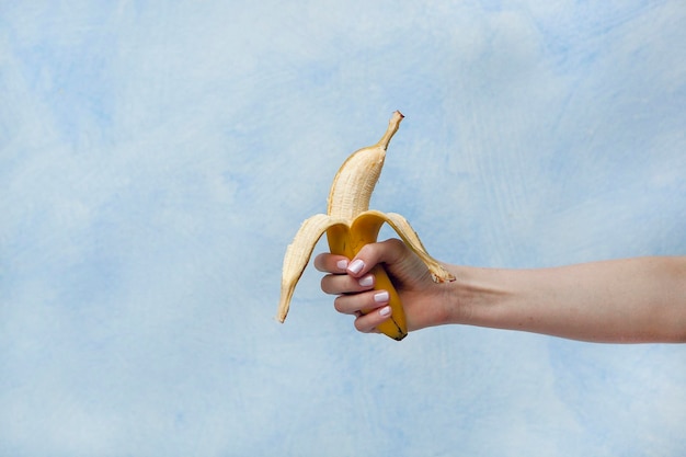 Primer plano de una mujer sosteniendo un plátano contra el cielo