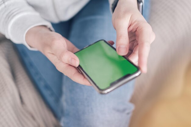 Un primer plano de una mujer con un teléfono de llave cromada sentada en un sofá