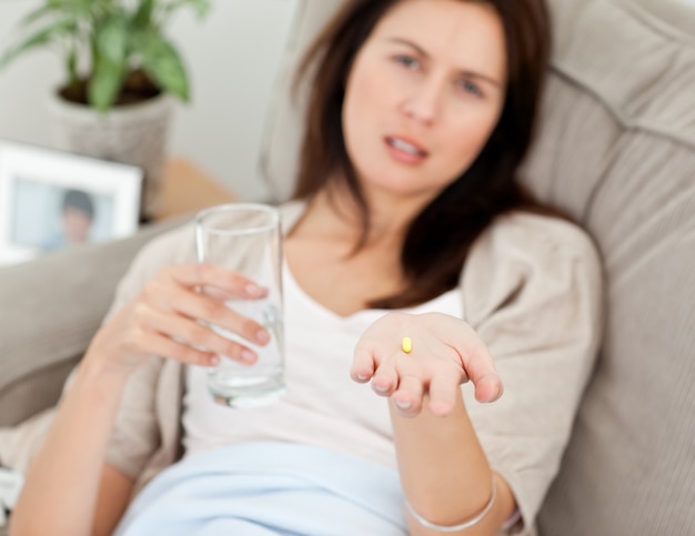 Primer plano de una mujer tomando su medicina en el sofá
