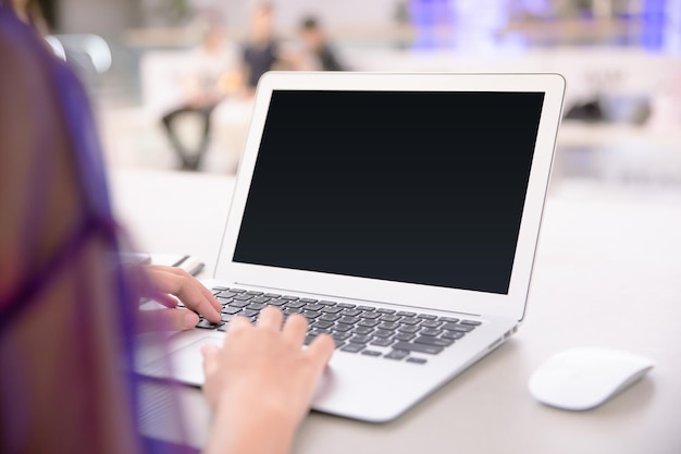 Primer plano de una mujer usando una computadora portátil en el escritorio de la oficina