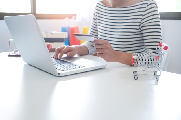 Primer plano de una mujer usando una computadora portátil mientras sostiene una tarjeta de crédito