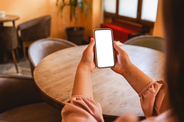 Primer plano de una mujer usando un teléfono celular enviando masajes en la cafetería