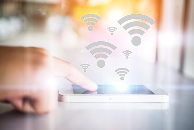 Primer plano de una mujer usando un teléfono móvil con el símbolo wifi en la mesa
