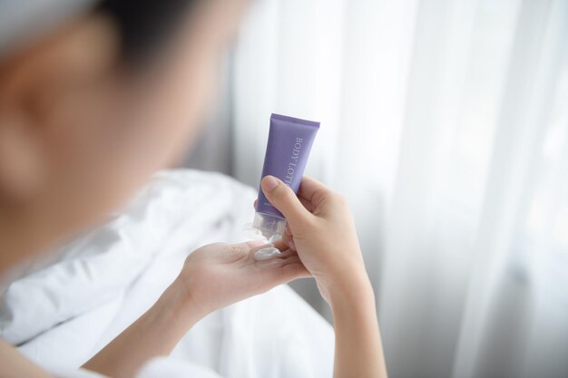 Primer plano de mujeres aplicando crema de loción corporal en la mano