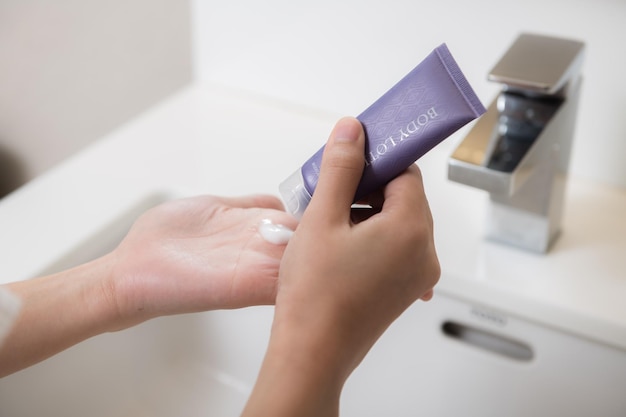 Primer plano de mujeres aplicando crema de loción corporal en la mano