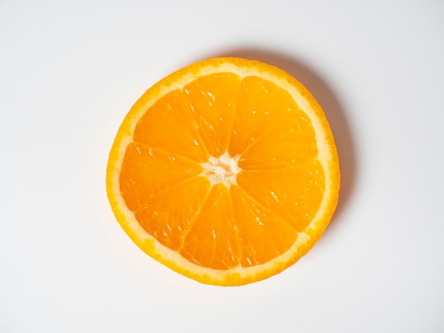Un primer plano de una naranja cortada en rodajas se encuentra sobre un fondo blanco Deliciosa fruta hermosa llena de vitaminas Foto de estudio vista superior plana