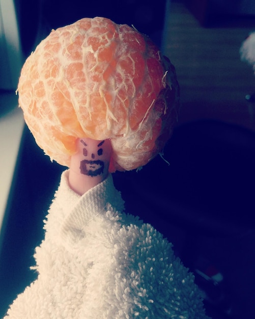 Foto primer plano de naranja en el pulgar con cara antropomórfica envuelta en una servilleta