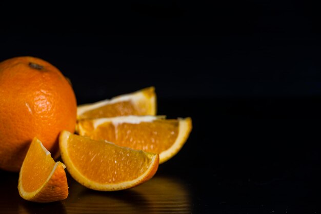 Primer plano de naranjas cortadas en la mesa contra un fondo negro