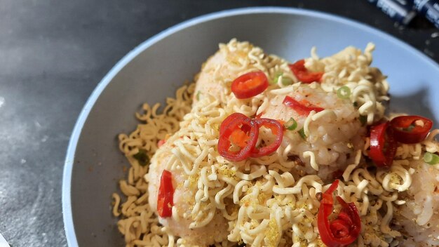 Primer plano de Nasi Kepal con una pizca de migas de fideos y rodajas de chile rojo 03