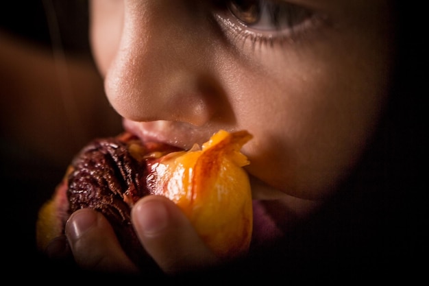 Primer plano de una niña comiendo fruta