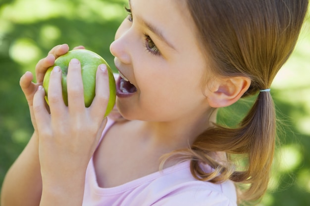 Primer plano de una niña comiendo manzana en el parque