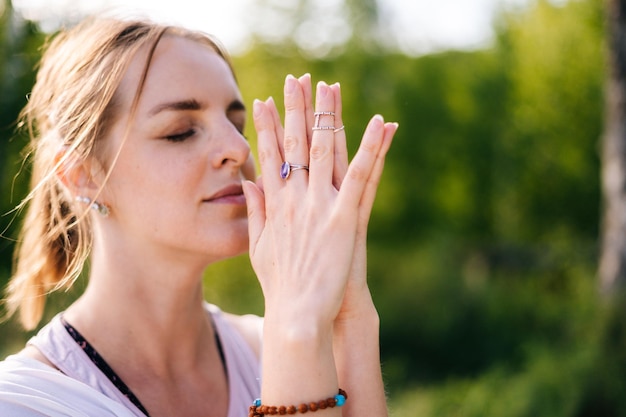 Primer plano de una niña con emoción de serenidad y tranquilidad realizando el gesto de Namaste