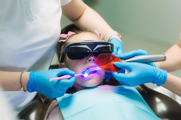 Primer plano de una niña con gafas VR y auriculares inalámbricos sentados en un sillón dental