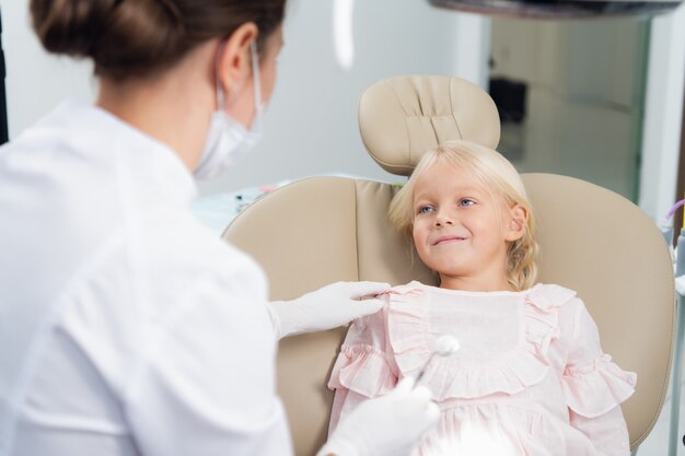 Primer plano de una niña que hace que un médico no identificado revise sus dientes