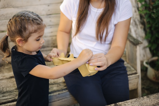 Primer plano de una niña con su mamá preparando cartón para reciclar la basura de clasificación familiar en casa