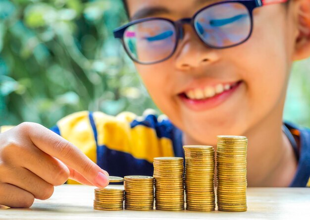 Foto primer plano de un niño apilando monedas en la mesa