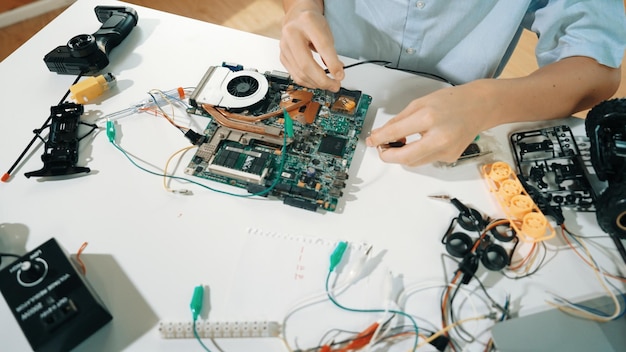 Primer plano de un niño arreglando la placa base con una herramienta electrónica en la mesa Edificación