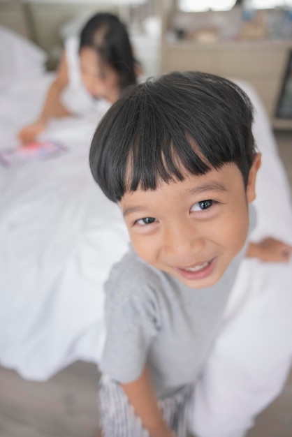 El primer plano de un niño asiático sonriente mira en la cámara con ropa gris