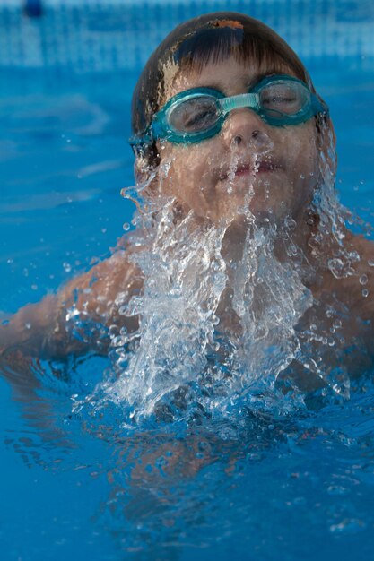 Foto primer plano de un niño sin camisa nadando en la piscina