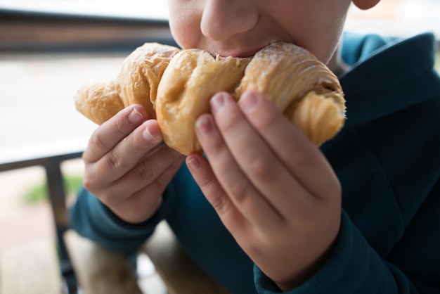 Primer plano de un niño comiendo un croissant Foto recortada