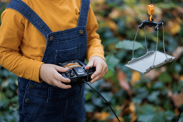 Foto el primer plano de un niño controla el control remoto por radio en el clima soleado de otoño controles para niños