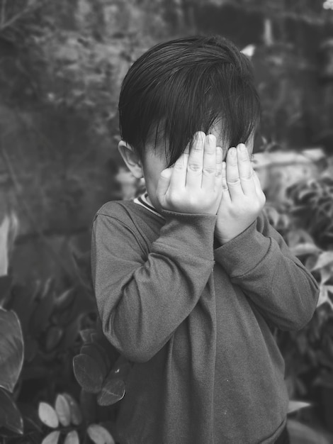 Foto primer plano de un niño cubriendo su cara