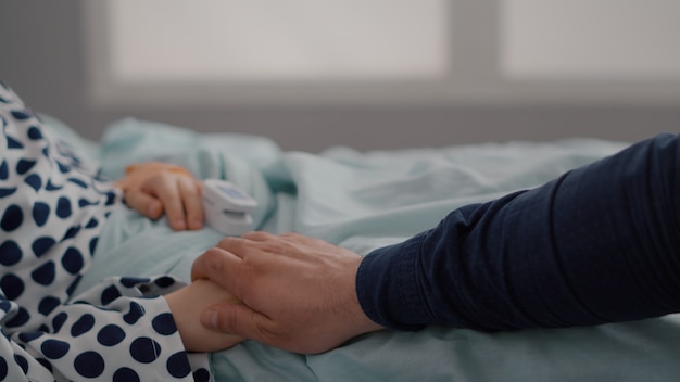 Primer plano de un niño enfermo descansando en la cama con el oxímetro en el dedo que monitorea el pulso del corazón después de sufrir ...