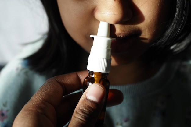 Primer plano de un niño enfermo usando un aerosol de medicina nasal